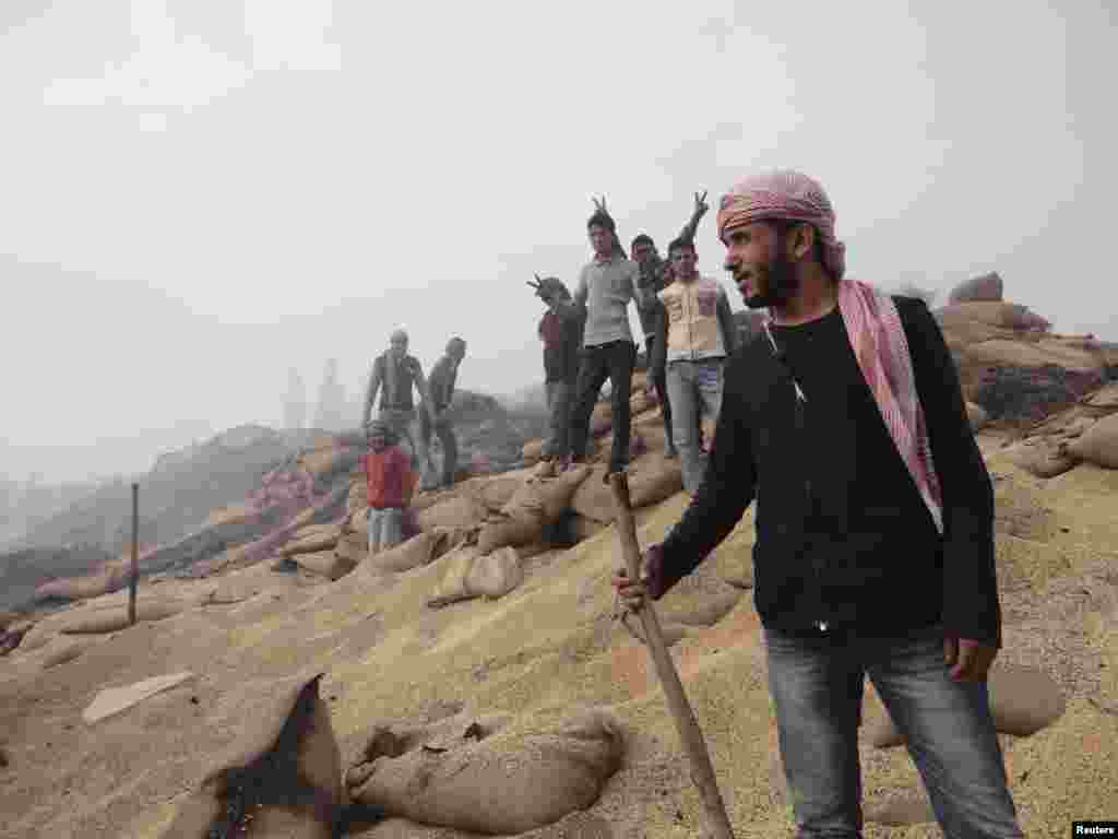 Residents pose near damaged wheat sacks after Syrian Air Force fighter jets fired missiles at the town of Ras al-Ain, Syria, November 26, 2012. 