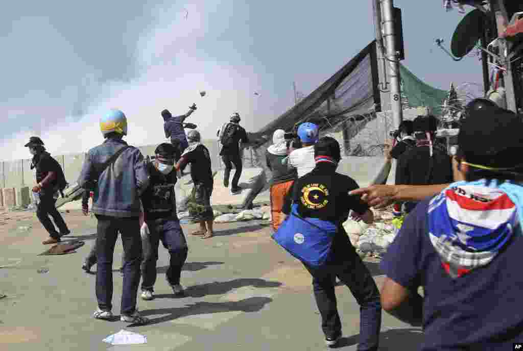 Anti-government protesters throw rocks after riot police fired tear gas at them near the Government House in Bangkok, Dec. 2, 2013. 