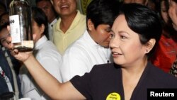 Mantan presiden Filipina Gloria Macapagal Arroyo memegang botol berisi lambanog, anggur lokal dari kelapa, di Manila. (Foto: Dok)