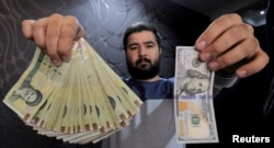 A money changer poses with a U.S dollar (R) and the equivalent in Iranian rials (L) in Tehran's business district, Iran, Jan. 20, 2016.