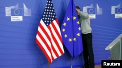 FILE - A worker adjusts European Union and U.S. flags in Brussels.