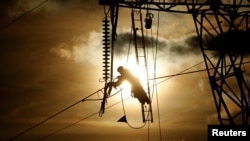 A technician works on an electricity pylon as part of maintenance of high-tension electricity power lines, during sunset in Roye, France, February 11, 2019. 