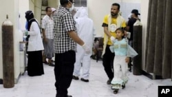 Yemeni medical workers wearing masks and protective gear talk to patients at hospital in Aden, where people have been dying by the dozens each day.
