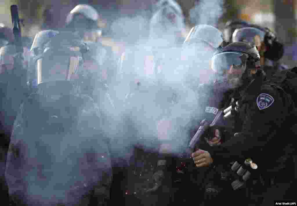 Israeli riot police fire tear gas at Israeli Arab and Palestinians activists during a protest against the Prawer Plan plan to resettle Israel&rsquo;s Bedouin minority from their villages in the Negev Desert, in the village of Arara.