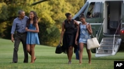 From left, President Barack Obama with daughter Malia and first lady Michelle Obama with daughter Sasha, walk form Marine One across the South Lawn of the White House in Washington, Sunday, Aug. 23, 2015.