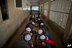 FILE - Pakistani students eat their lunch at their madrassa in Islamabad, Pakistan, Feb. 1, 2015.