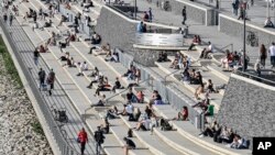 រូបឯកសារ៖ មនុស្សជាច្រើនានាក់ សម្រាកលំហែកាយនៅមុខទន្លេក្នុងទីក្រុង Cologne ប្រទេសអាល្លឺម៉ង់ កាលពីថ្ងៃទី២៧ ខែមេសា ឆ្នាំ២០២០ បើទោះបីជាមានបញ្ជាឲ្យពលរដ្ឋរក្សាគម្លាតពីគ្នាដើម្បីទប់ស្កាត់ការឆ្លងរាលដាលនៃវីរុសកូរ៉ូណាក្តី។