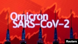 Jeringas se ven frente un gráfico de acciones que se muestra junto a las palabras "Omicron SARS-CoV-2" en esta ilustración tomada el 27 de noviembre de 2021. 