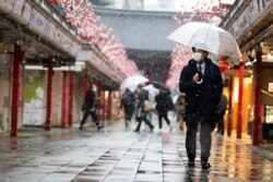 A man wearing a face mask walks through the Sensoji temple in the snow in Tokyo, Jan. 28, 2021.