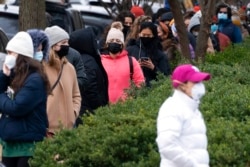 People stand in a line spanning several blocks for COVID-19 testing, at a Curative testing kiosk outside an elementary school in northwest Washington, Dec. 21, 2021.
