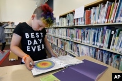 Sam, 9 tahun, membaca buku di perpustakaan Bay Area Rainbow Day Camp di El Cerrito, California, 12 Juli 2017. (Foto: AP)