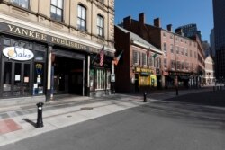 A block of closed restaurants on a deserted street ends at Faneuil Hall, right, Saturday, April 4, 2020, in Boston. The area is usually busy with tourists, but tourism is nearly non-existent during the coronavirus outbreak.