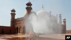 FILE - Volunteers disinfects the historical Badshahi Mosque ahead of the Muslim fasting month of Ramadan, in Lahore, Pakistan, April 22, 2020. 