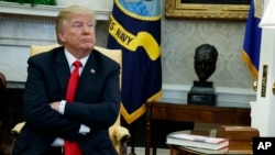 President Donald Trump listens during a meeting with North Korean defectors where he talked with reporters about allowing the release of a secret memo on the FBI's role in the Russia inquiry, in the Oval Office of the White House, Feb. 2, 2018, in Washington.