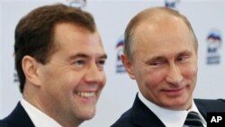 Russian President Dmitry Medvedev, left, and Russian Prime Minister Vladimir Putin participate in a video conference with regional offices of the United Russia party, at the party's headquarters, Moscow, October 21, 2011.