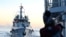 FILE - A Philippines coast guard member looks at the Chinese Coast Guard vessel as they come close during a mission to deliver provisions at Second Thomas Shoal in the South China Sea on November 10, 2023.