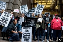 FILE - Activists hold signs containing the image of Turing Pharmaceuticals CEO Martin Shkreli in front the building that houses Turing's offices, during a protest in New York highlighting pharmaceutical drug pricing, Oct. 1, 2015.
