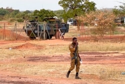 FILE - A Burkinabe soldier walks past a French Armoured Personnel Carrier, part of a French military convoy, heading to Niger, stopped by protesters in Kaya, Burkina Faso, Nov. 20, 2021.