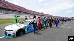 Nascar drivers Kyle Busch, left, and Corey LaJoie, right, join other drivers and crews as they push the car of Bubba Wallace to the front of the field prior to the start of the NASCAR Cup Series auto race at the Talladega Superspeedway, June 22, 2020. 
