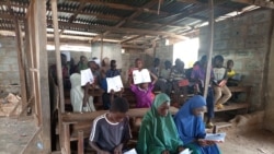 Children hold up a translated version of the COVID-19 children's book in a village in Karonmajiji, Abuja, Nigeria, Sept. 28, 2021. (Timothy Obiezu/VOA)