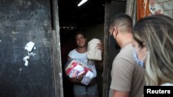 Daniele de Fatima, stands at her house in Cidade de Deus slum, as she receives food and bread from members of the Institute doAcao, which was produced at the Santuario de Nossa Senhora de Fatima, amid COVID-19 outbreak, in Rio de Janeiro, June 24, 2021.