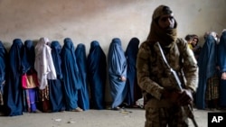 ফাইল- মানবিক সহায়তা গোষ্ঠীর বিতরণ করা খাদ্য গ্রহণে অপেক্ষাকৃত নারীদের পাহারা দিচ্ছে একজন তালিবান যোদ্ধা। কাবুল, আফগানিস্তান, মে ২৩,২০২৩।
