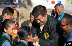 FILE - President of the Tibetan administration in exile Lobsang Sangay, center, greets a child as he arrives to attend the founding anniversary celebrations at the Tibetan Children's Village School in Dharmsala, India, Oct. 23, 2017.