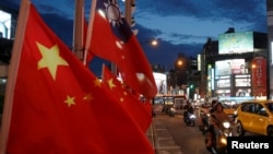 FILE - Flags of China and Taiwan flutter next to each other during a rally calling for peaceful reunification, days before the inauguration ceremony of President Tsai Ing-wen, in Taipei, Taiwan, May 14, 2016.
