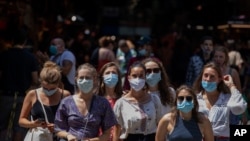 Tourists wearing face masks wait to cross a road in downtown Barcelona, Spain, July 16, 2020.