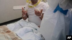 Un paciente habla con los médicos mientras está acostado en su cama en la sala de emergencias COVID-19 en el hospital Mellino Mellini en Chiari, en el norte de Italia, el lunes 8 de marzo de 2021.