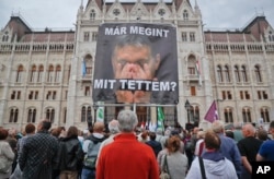 FILE - A man holds a poster of Hungarian Premier Viktor Orban that reads "What have I done again" during a protest by opposition parties against Orban's policies on migrants in Budapest, Hungary, Oct. 2, 2016.