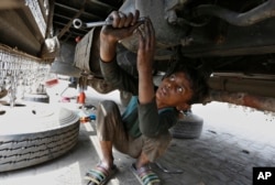 FILE - A 10-year-old boy works at an automotive repair shop in Lahore, Pakistan, to earn living for his family, June 12, 2021.
