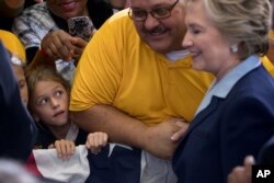 A girl looks at Democratic presidential candidate Hillary Clinton as she greets members of the audience at a rally at the Downtown Toledo Train Station in Toledo, Ohio, Oct. 3, 2016.