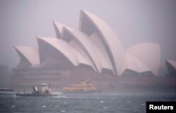 Feri dan kapal melintas di depan Sydney Opera House saat angin kencang dan hujan lebat melanda kota Sydney, Australia, 28 November 2018. (Foto: Reuters)