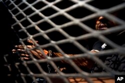 A man who is part of the Central American migrant caravan sits inside a police wagon after being detained for smoking marijuana according to the police, in Tijuana, Mexico, Nov. 21, 2018. The actions of a few appear to be tarnishing the image of the 6,000 migrants who are camped in Tijuana.