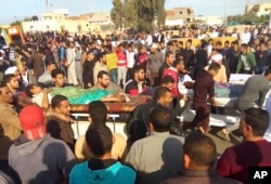 FILE - Injured people are evacuated from the scene of a militant attack on a mosque in Bir al-Abd in the northern Sinai Peninsula of Egypt, Nov. 24, 2017.