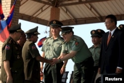 FILE - Cambodian Defense Minister Tea Banh, second left, shakes hands with a Chinese army adviser during a graduation ceremony at the Army Institute in Kampong Speu province. Cambodia has backed Chinese maritime claims across islands and waters in the South China Sea.