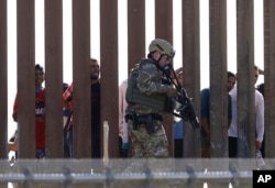 FILE - A U.S. Customs and Border Protection officer walks along a wall at the border between Mexico and the United States, as seen from San Diego, California, Nov. 25, 2018.