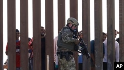 FILE - A U.S. Customs and Border Protection officer walks along a wall at the border between Mexico and the United States, as seen from San Diego, California, Nov. 25, 2018.