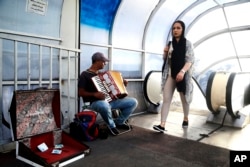 A street musician plays music as a woman makes her way in downtown Tehran, Iran, July 30, 2018. Iran's currency has dropped to a record low ahead of the imposition of renewed American sanctions.