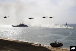 FILE - Russian navy ships and helicopters take a part in a landing operation during military drills at the Black Sea coast, Crimea, Sept. 9, 2016.