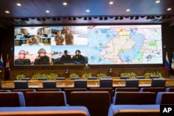 Lt.-Gen. Sergei Rudskoi, center, of the Russian Military General Staff listens to Russian and Syrian officers during a video call, as a Syrian army facility is displayed on screen, at a Russian Defense Ministry building in Moscow, Russia, Sept. 12, 2016.