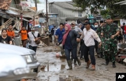 People feared by tsunami run in panic on a street in Sumur village, Indonesia, Dec. 25, 2018.
