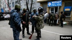 Armed men stand in front of police headquarters in Slaviansk, April 12, 2014.
