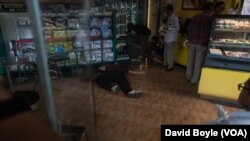 Police survey the crime scene where Kem Ley was shot dead while family members pray next to his dead body, July 10, 2016.