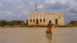 Une soudanaise traverse une zone inondée, à la suite d'inondations et de pluies torrentielles, dans la ville d'Osaylat, à 50 km au sud-est de la capitale Khartoum, le 6 août 2020.