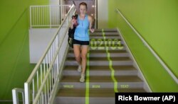 Utah Valley University student Jody Nelson walks down the bright green lanes painted on the stairs from the gym with her phone in her hand on Thursday, June 18, 2015, at Utah Valley University, in Orem, Utah.