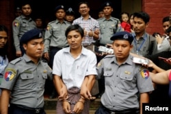 Detained Reuters journalist Kyaw Soe Oo and Wa Lone are escorted by police as they leave after a court hearing in Yangon, Myanmar, August 20, 2018.