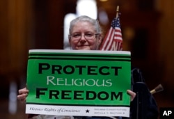 FILE - Condy Holmes of Mechanicsburg, Ind. holds a sign a rally at the Statehouse in Indianapolis, Indiana.
