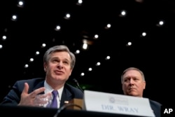 FBI Director Christopher Wray, accompanied by CIA Director Mike Pompeo, right, speaks at a Senate Select Committee on Intelligence hearing on worldwide threats, in Washington, Feb. 13, 2018.
